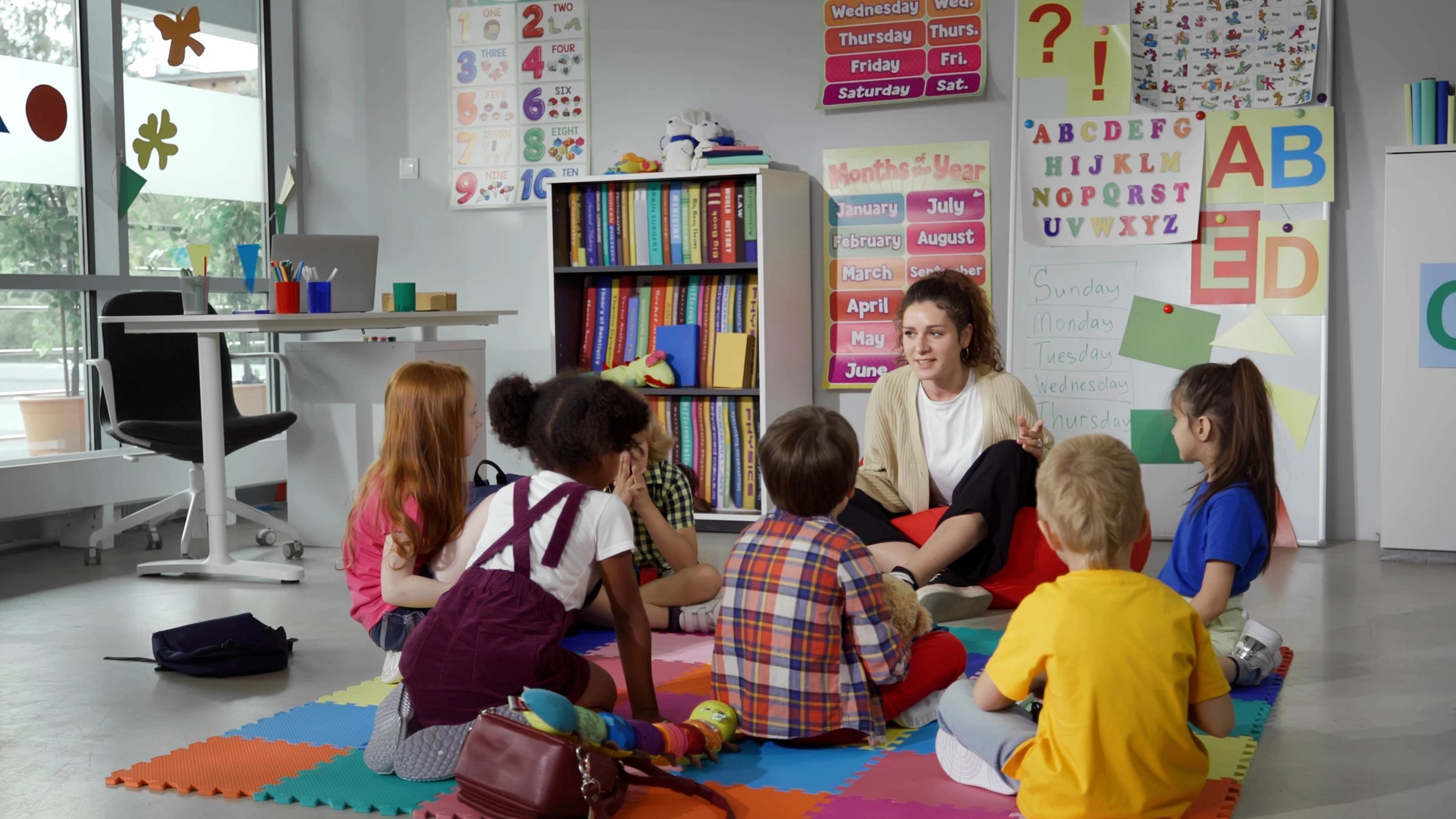 Small nursery school children with teacher sitting on floor havinga lesson