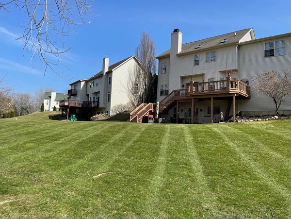 Row of suburban houses with wooden decks and freshly mowed lawns under a clear blue sky.
