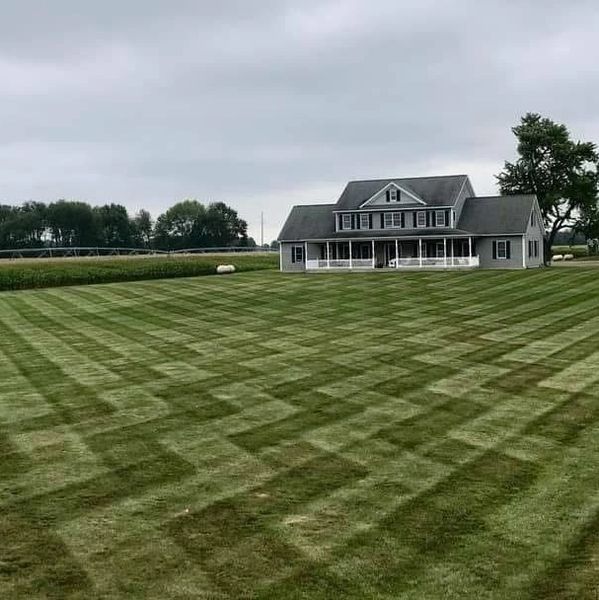 A large house with a uniquely patterned lawn under a cloudy sky.