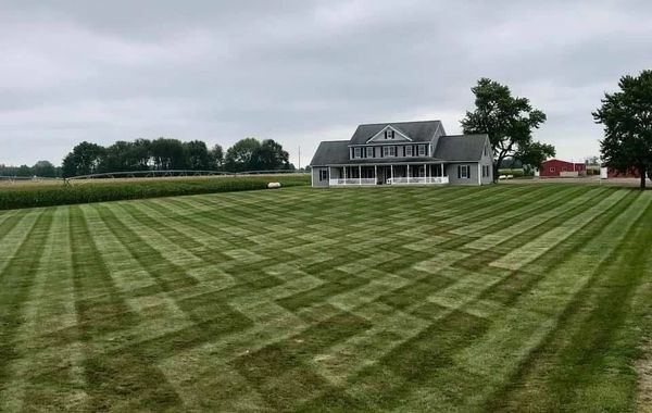 A house with a large, intricately patterned lawn under a cloudy sky.