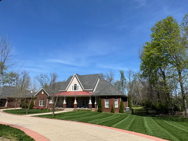 Spacious brick house with manicured lawn and clear blue sky.
