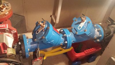 Blue valve assembly on red support stands indoors.