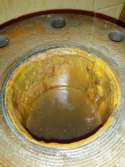 Close-up of a rusty, corroded metal component with holes.