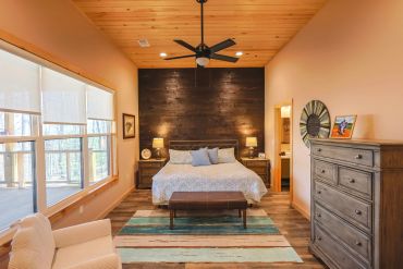Cozy bedroom with wooden accents and large windows.