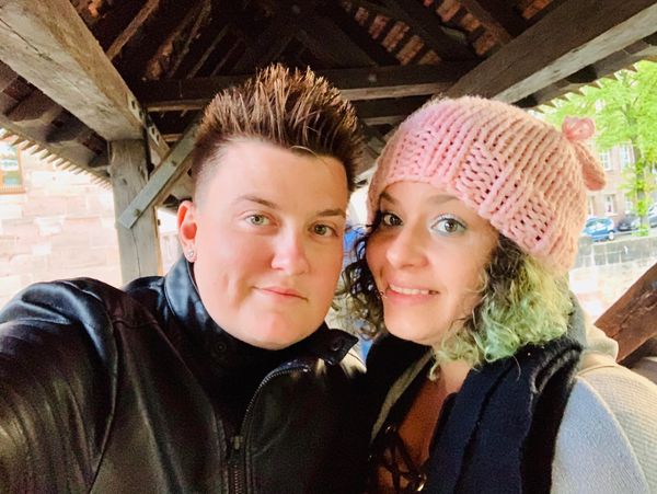 Two people smiling under a wooden roof structure.