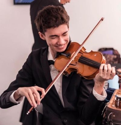 Young man happily playing the violin.