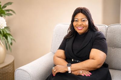 Smiling woman sitting on a couch with folded arms.