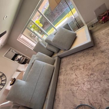 Disassembled gray sectional couch in living room.