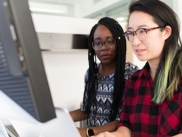 Two girl working on each other and looking on the computer