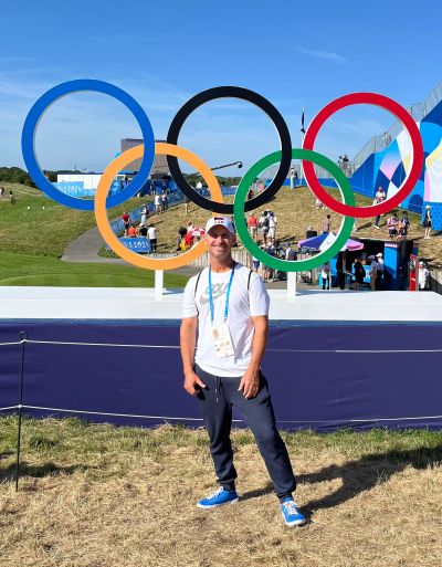 Man posing in front of Olympic rings.