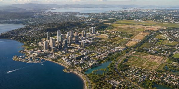 Aerial view of a coastal city with tall buildings and green areas.