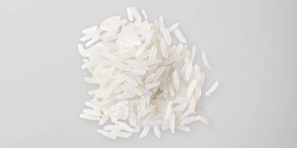 A small pile of uncooked white rice grains on a light gray background.