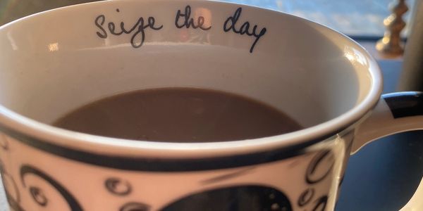 A coffee cup with 'Seize the day' written inside, overlooking a sunlit balcony.