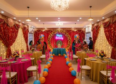 Colorful birthday party setup with balloons, flowers, and guests in traditional attire.