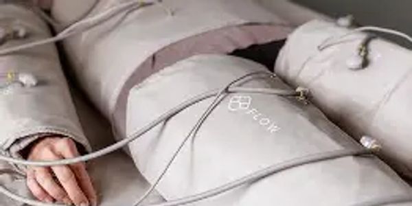 Person undergoing a compression therapy session with connected leg sleeves in FLOWpresso lymphatic drainage suit.