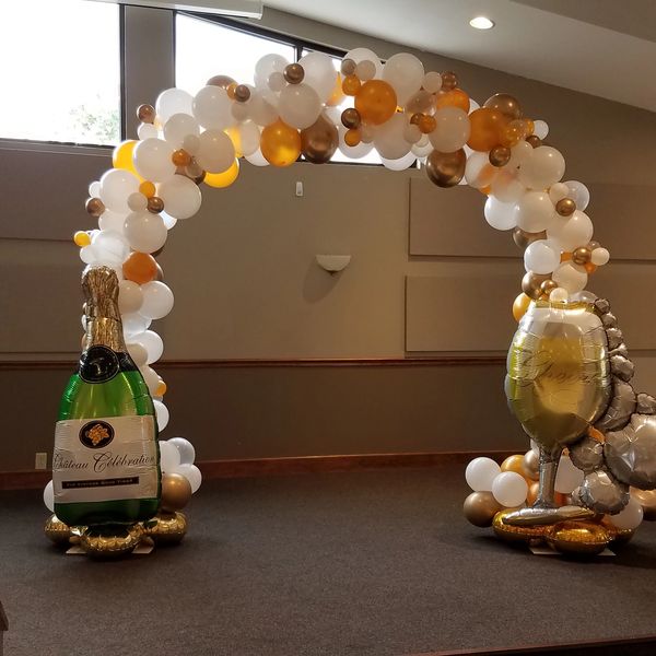 Decorative balloon arch with champagne and glass balloons for celebration.