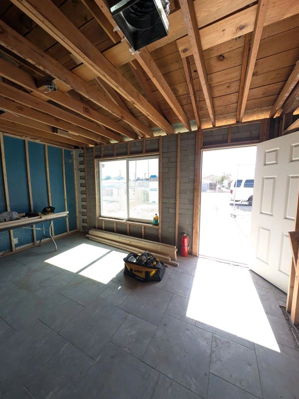 Room under construction with exposed wooden beams and construction tools.