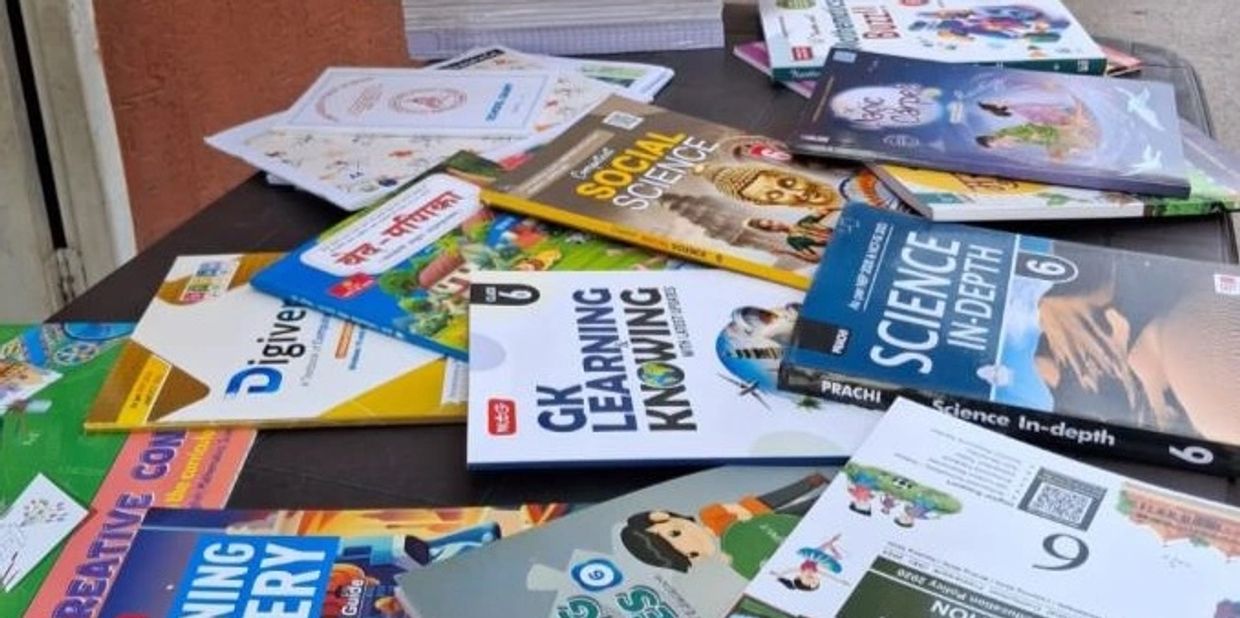 A variety of educational books spread on a table, covering subjects like social science and science.