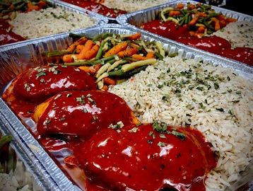 Repas de poulet farcis servis avec riz et légumes du jardin dans un contenant en aluminuim