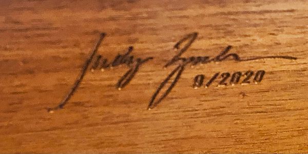 Signature and date written on a wooden surface.