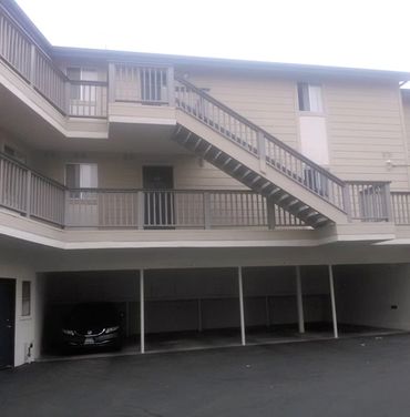 Exterior apartment stairs and covered parking area.