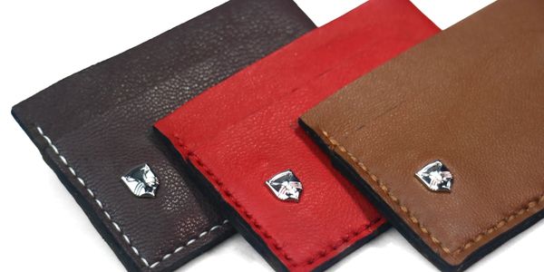 Three leather wallets in black, red, and brown with metal cat logos.