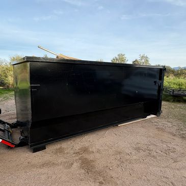 Large black metal container on dirt ground outdoors.