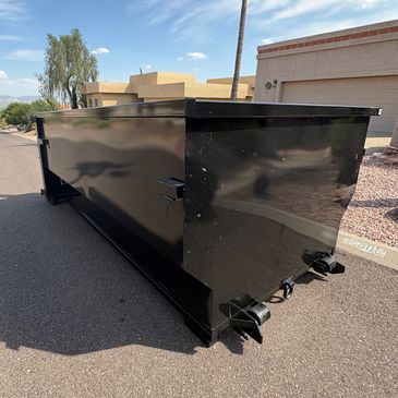 Black dumpster on a residential street.