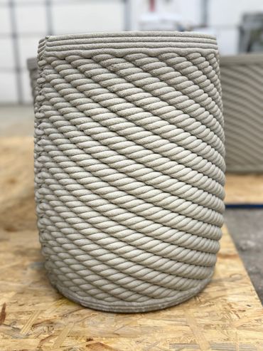 This flower pot has a rope twist to it.