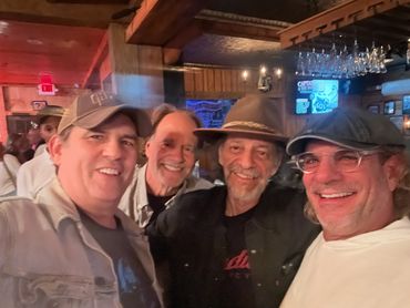 Four smiling men posing for a selfie in a cozy bar.