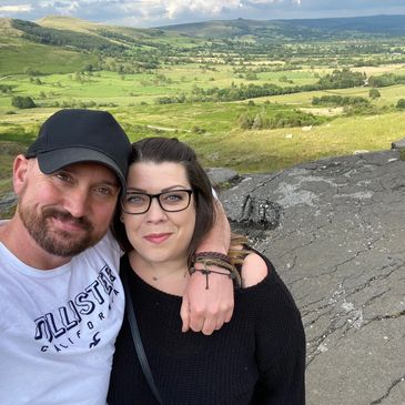 Couple taking a selfie with a scenic countryside backdrop.