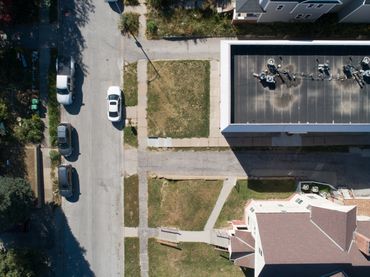 Aerial view of a residential street with parked cars and houses.