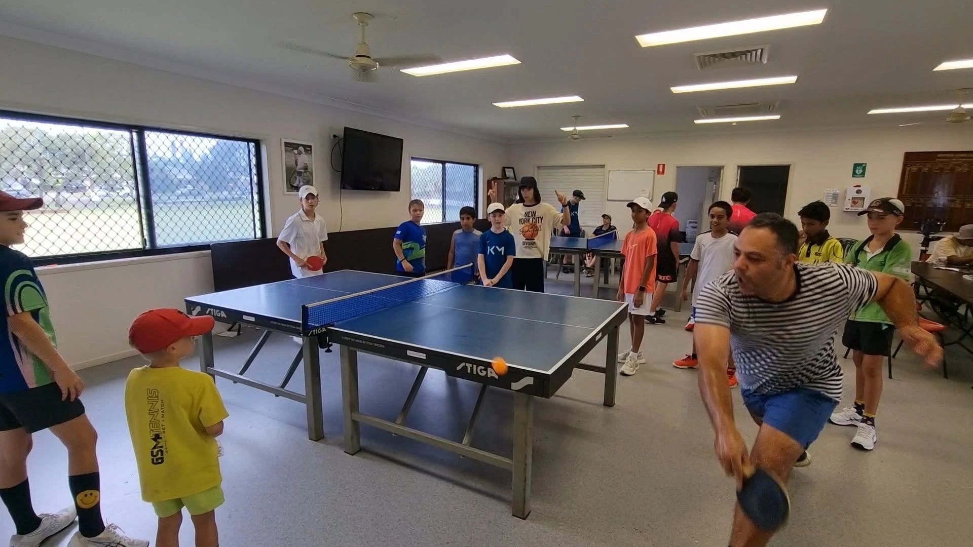 Group playing table tennis indoors.