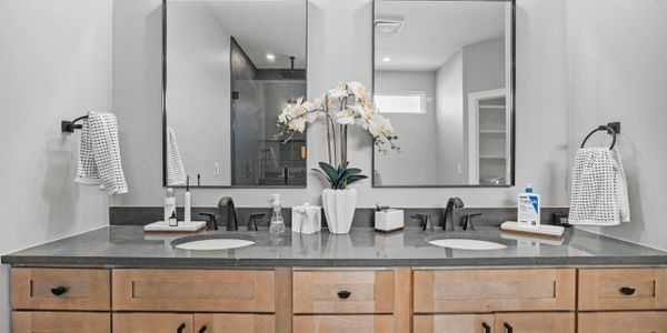 Modern double vanity bathroom with wooden cabinets and large mirrors.