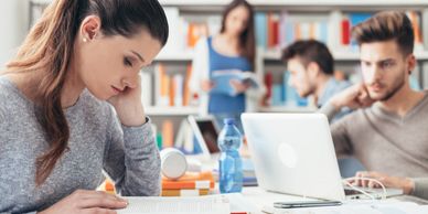 Students sitting at the desk and studying together using laptops,