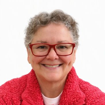 Smiling woman with short gray hair and red glasses.