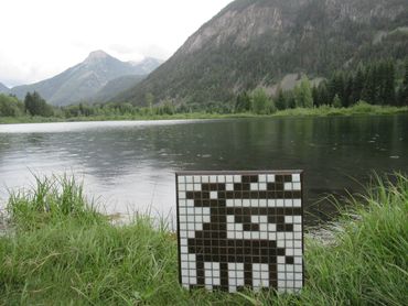 Installation of reindeer mosaic, with lake and mountains in the background