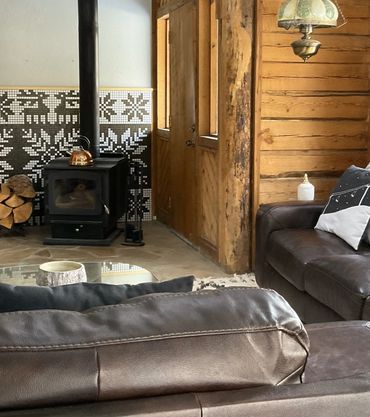 Log cabin living room with leather couches, wood-burning fireplace and mosaic mural