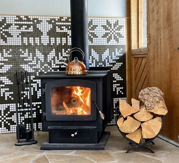 Mosaic mural with Nordic patterns featuring reindeer and snowflakes, behind wood-burning fireplace