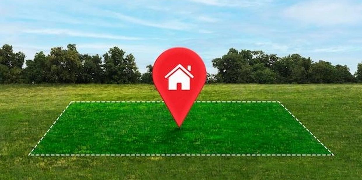 Empty plot of land marked with a home location pin symbol.
