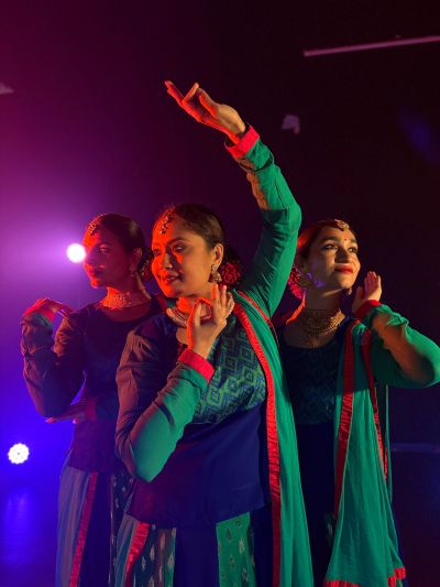 Three women in traditional attire dancing on stage.