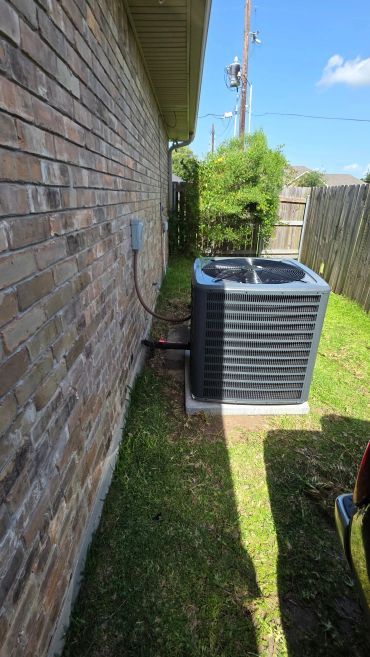 Outdoor air conditioning unit beside a brick house.