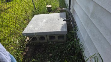 Concrete block structure beside a house and fence.