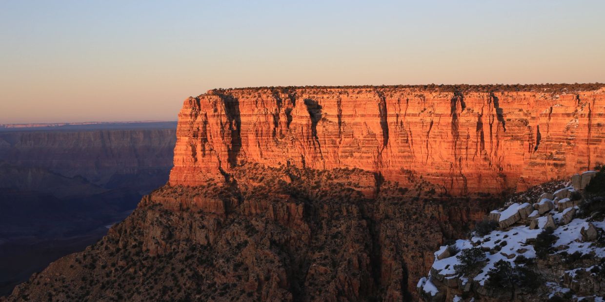 Sunlit rock face of a canyon at sunset.