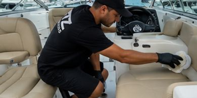 A man cleaning the interior of a boat with a cloth.