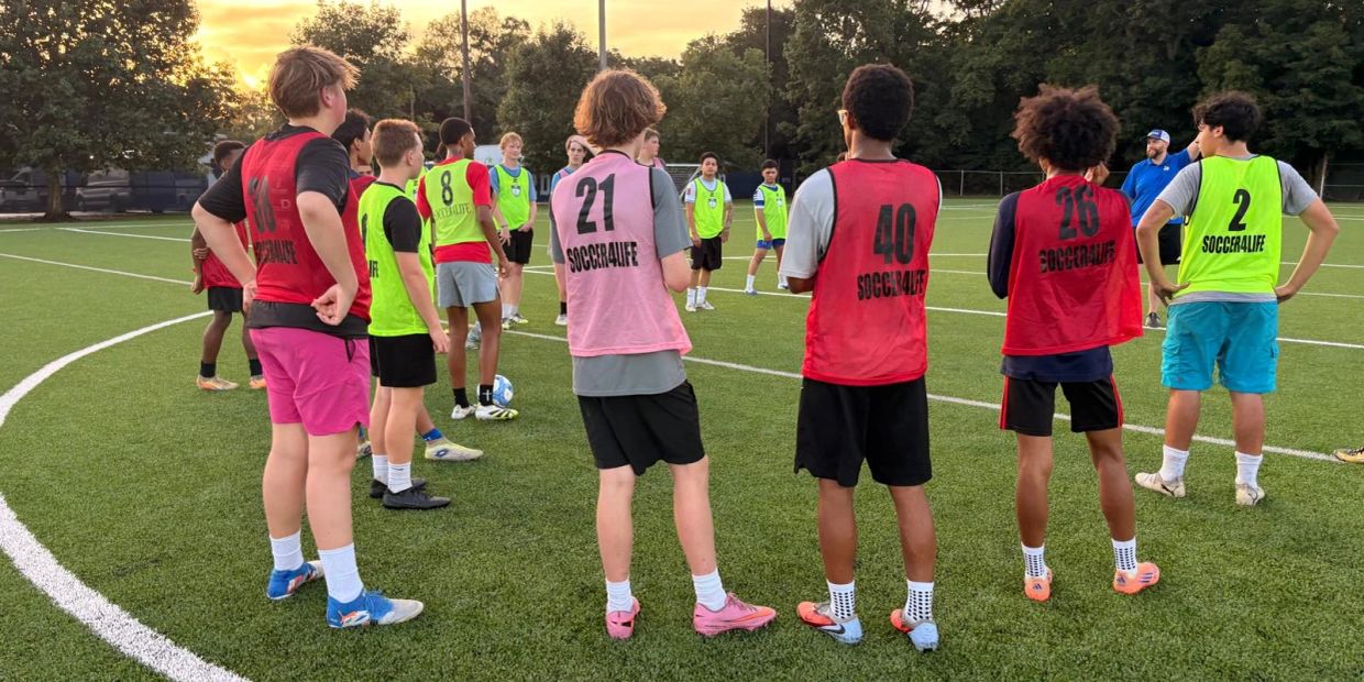 Youth soccer players in colored jerseys on a field at sunset.