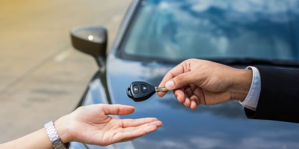A vehicle dealer giving the key of a new car to a client