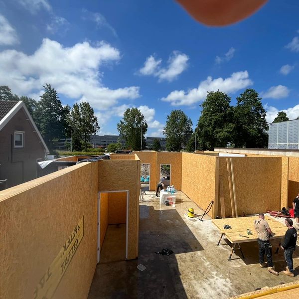 Construction site of a building with wooden walls under blue sky.