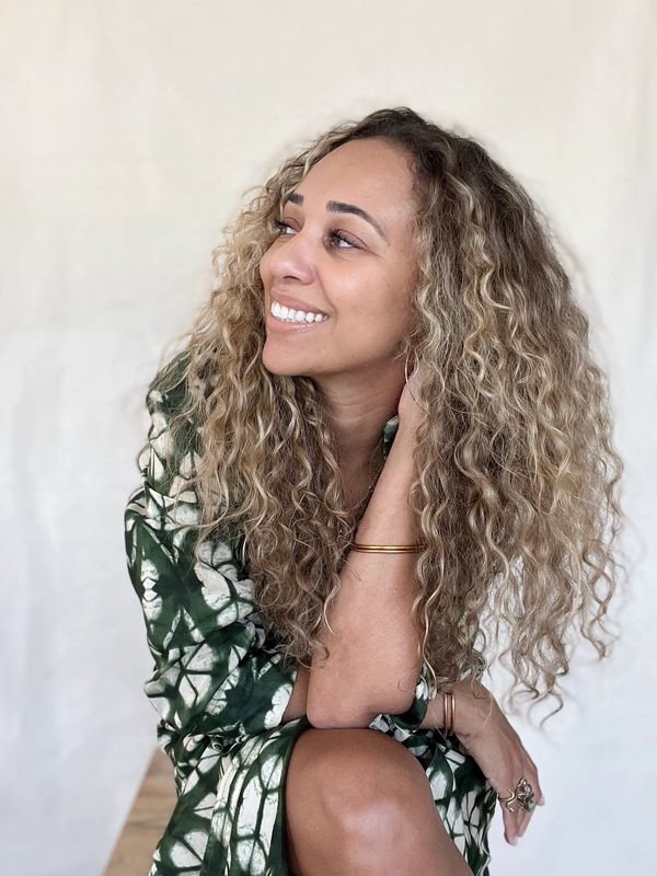 A woman sitting and smiling, certified Reiki Master Teacher and healing artist