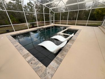 Modern pool with two white lounge chairs under a screened enclosure.